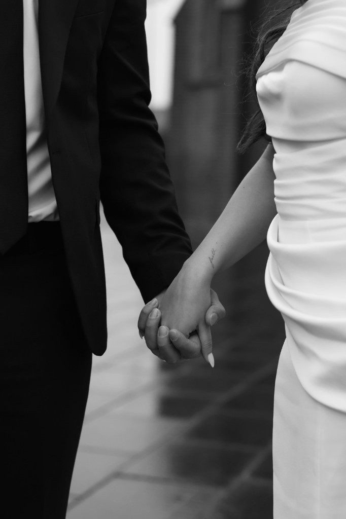 Bruidspaar wandelt hand in hand, zwart-wit