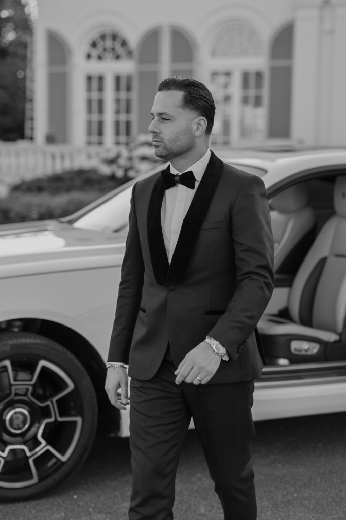 Bruidegom in smoking naast Rolls-Royce, zwart-wit